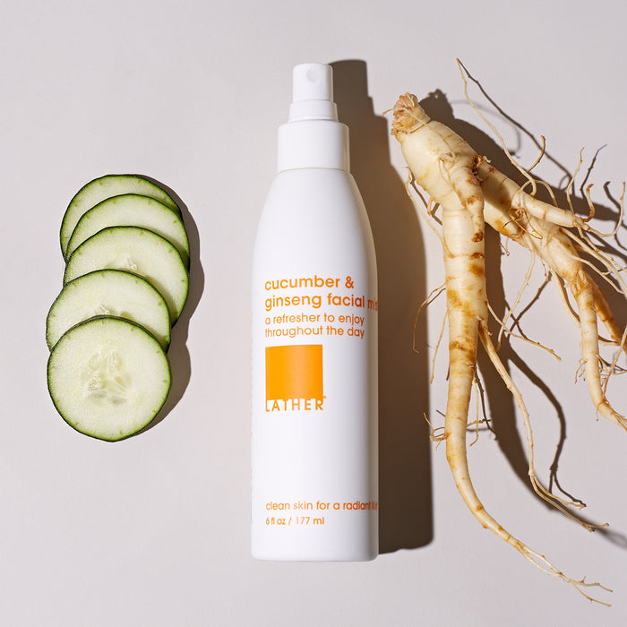 Cucumber and Ginseng Facial Mist bottle next to slices of cucumber and a raw ginseng root