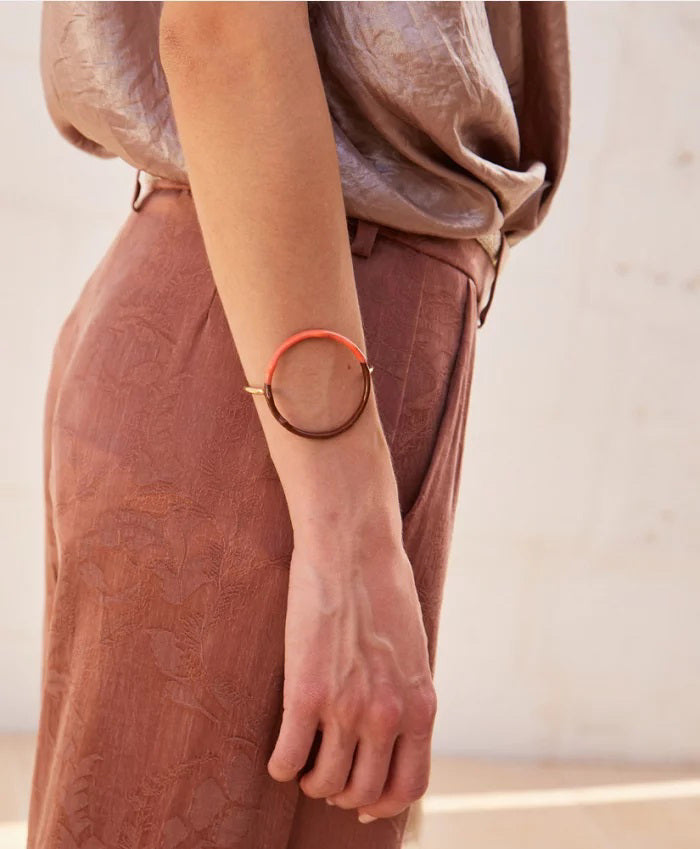 The MOMONI DIP DYE BRACELET is a gold electroplated accessory with an open circular design, featuring a glossy brown and orange resin ring accent, displayed on a plain white background.