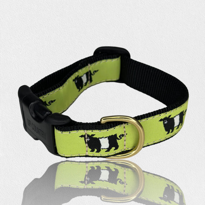 The FEARRINGTON SIGNATURE COLLECTION - BESPOKE BELTIE DOG COLLAR, LARGE by UP COUNTRY is a green adjustable collar with black and white cow designs, a black plastic buckle, and gold-toned D-ring, shown on a white background.