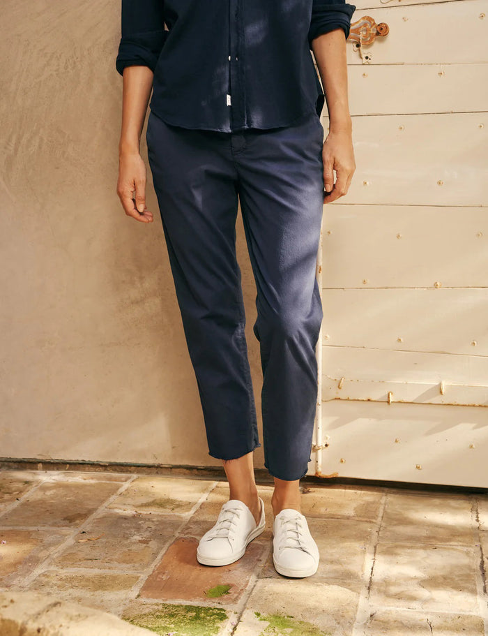 A pair of FRANK & EILEEN’s THE WICKLOW Italian Chinos in Performance Twill, featuring a navy blue color, straight legs, and raw unfinished hems, is laid flat on a light textured background for an Italy-meets-California vibe.