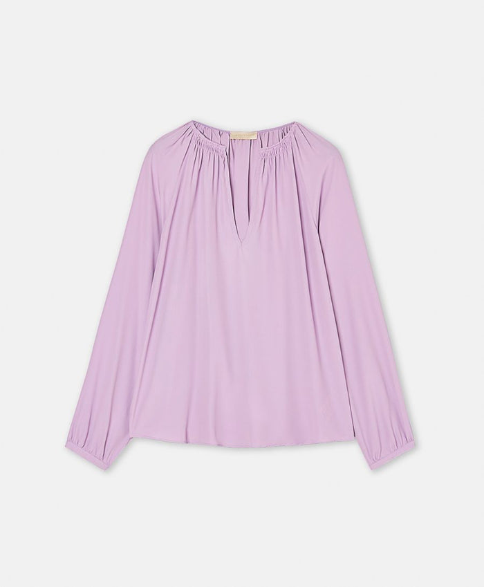 The MOMONI LARICE SHIRT is a long-sleeved, light purple bohemian blouse featuring a gathered neckline, subtle V-front slit, and loose fit, shown on a white background.