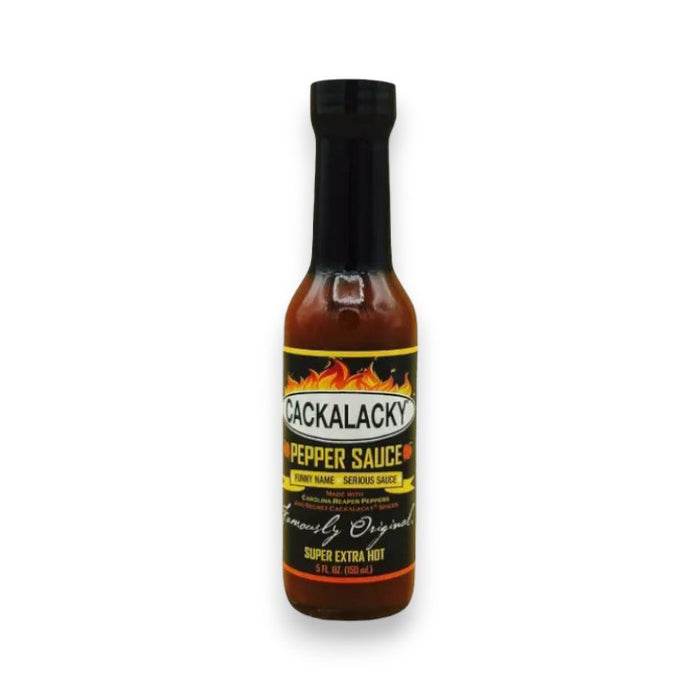 A bottle of CACKALACKY - PEPPER SUPER EXTRA HOT sauce by CACKALACKY, featuring a black cap and label with flames and "Super Extra Hot" text. The bottle contains reddish-brown Carolina reaper pepper sauce.