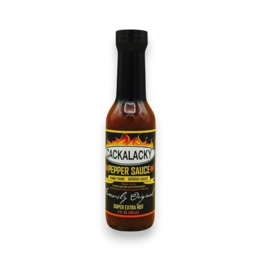 A bottle of CACKALACKY - PEPPER SUPER EXTRA HOT sauce by CACKALACKY, featuring a black cap and label with flames and "Super Extra Hot" text. The bottle contains reddish-brown Carolina reaper pepper sauce.