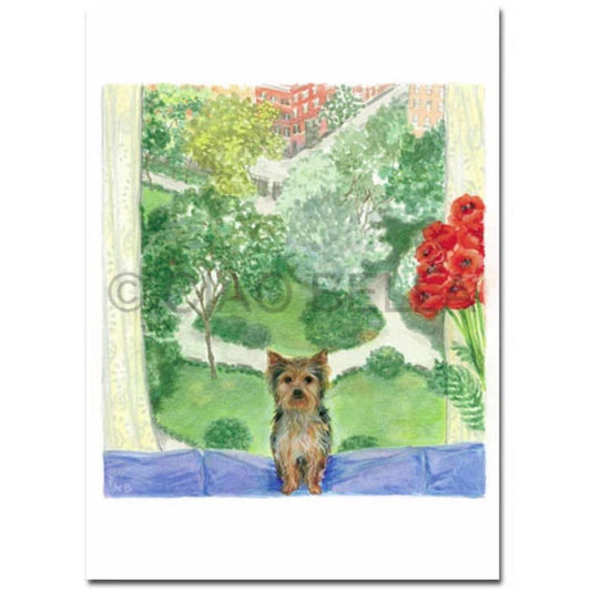 A small Yorkshire Terrier sits on a windowsill, with a CIAO BELLA - GRAMERCY PARK CARD by CIAO BELLA next to red flowers in a vase on the right, while a park and buildings are visible through the window behind it.