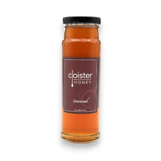 A jar of CLOISTER HONEY - SOURWOOD HONEY 12OZ is displayed against a white background. The cylindrical jar, filled with amber natural honey, has a black lid. The label, predominantly burgundy with white text, features the brand name "CLOISTER HONEY" and the variety "Sourwood," sourced from the Appalachian Mountains.
