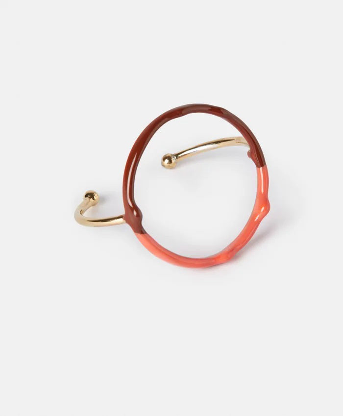 The MOMONI DIP DYE BRACELET is a gold electroplated accessory with an open circular design, featuring a glossy brown and orange resin ring accent, displayed on a plain white background.