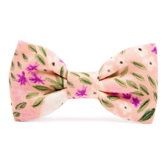 The Foggy Dog’s Harper Floral standard dog bow tie is a handmade pet accessory in pink, featuring green leaves, small brown dots, and purple flowers.