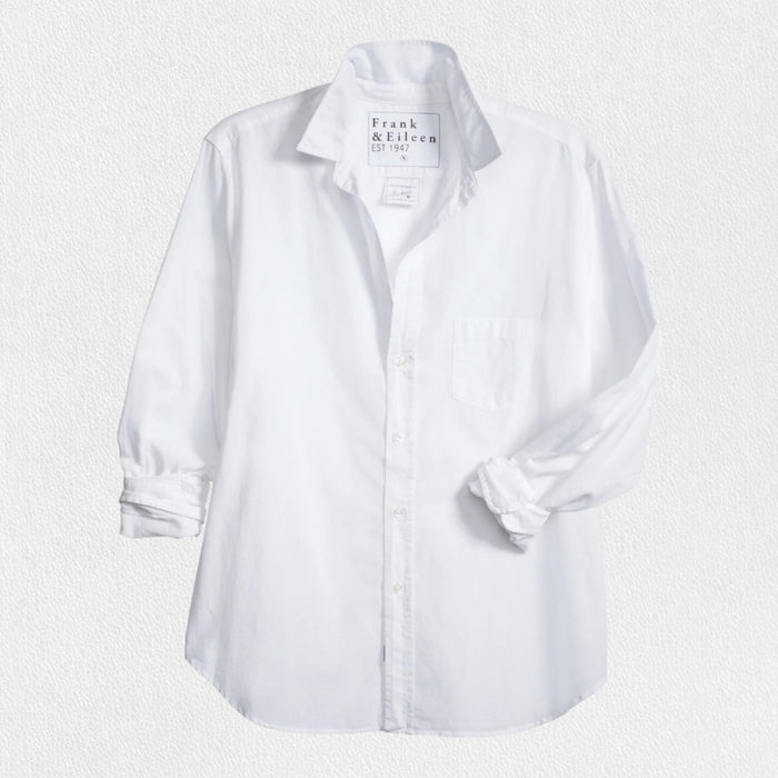 The EILEEN Relaxed Button-Up by Frank & Eileen features a white chambray fabric with long sleeves, a chest pocket, and bust-flattering buttons. The collar displays "Frank & Eileen EST. 1947," while the sleeves are slightly rolled for a casual look.