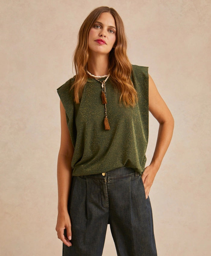 A woman with long brown hair wears the MOMONI LUREX JERSEY SLEEVELESS TOP in green, paired with dark jeans and a tassel necklace, standing against a neutral background.