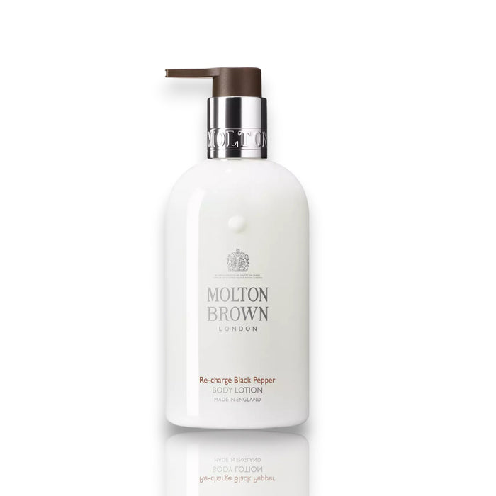 A white pump bottle of MOLTON BROWN RE-CHARGE BLACK PEPPER BODY LOTION with silver and brown accents stands upright on a white background, featuring bold black pepper and woody-citrus notes.