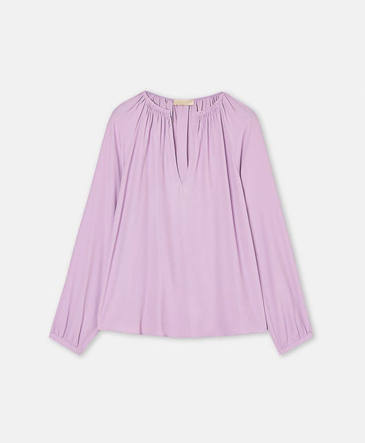 The MOMONI LARICE SHIRT is a long-sleeved, light purple bohemian blouse featuring a gathered neckline, subtle V-front slit, and loose fit, shown on a white background.