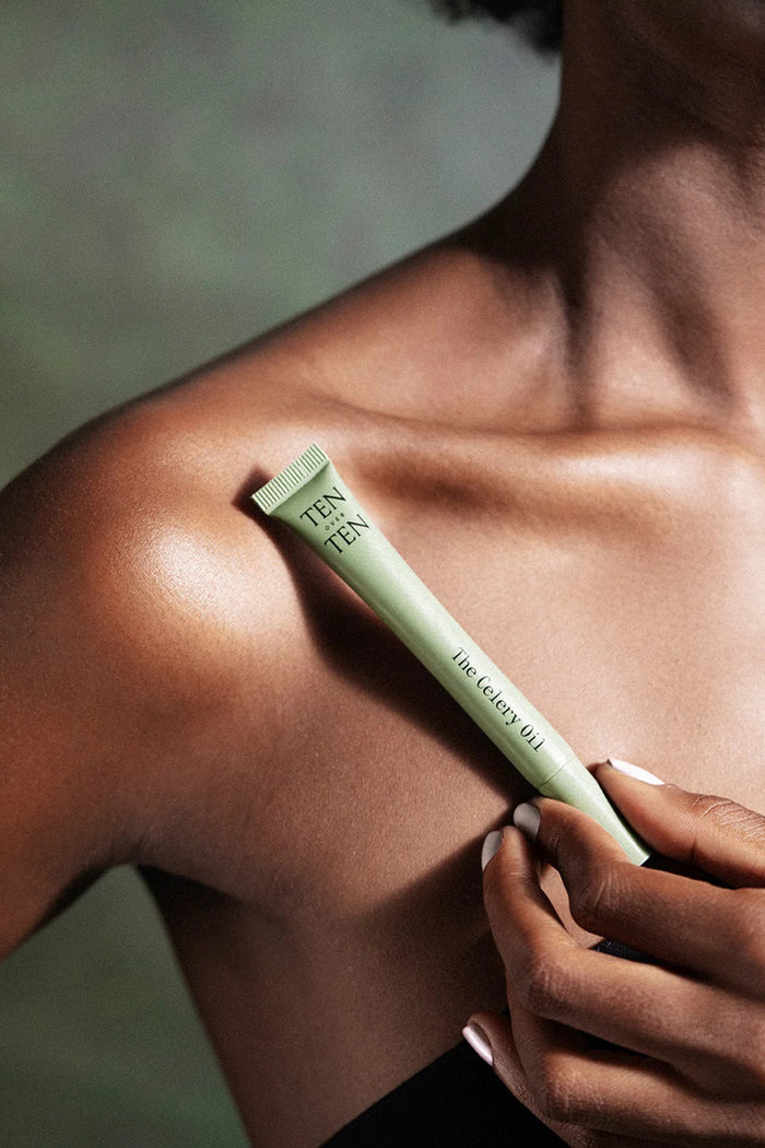 A light blue tube labeled "TENOVERTEN - THE CELERY OIL" by TEN OVER TEN, known for its nourishing nail treatment and repair benefits, rests uncapped on a beige surface.