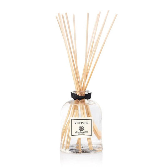 The VETIVER DIFFUSER by E WIGHTMAN & CO features a glass bottle with clear liquid and wooden reeds, topped with a black ribbon. This elegant low-VOC diffuser brings refined vetiver fragrance to your home.